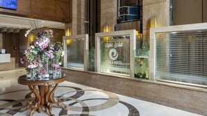 A lobby with a reception desk, a decorative table with vases, and a sign for the Fira Hotel. - Afraa Hotel (Makkah)