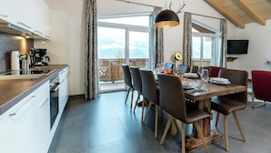 A modern kitchen with a dining area, wooden ceiling, and large windows overlooking a deck.