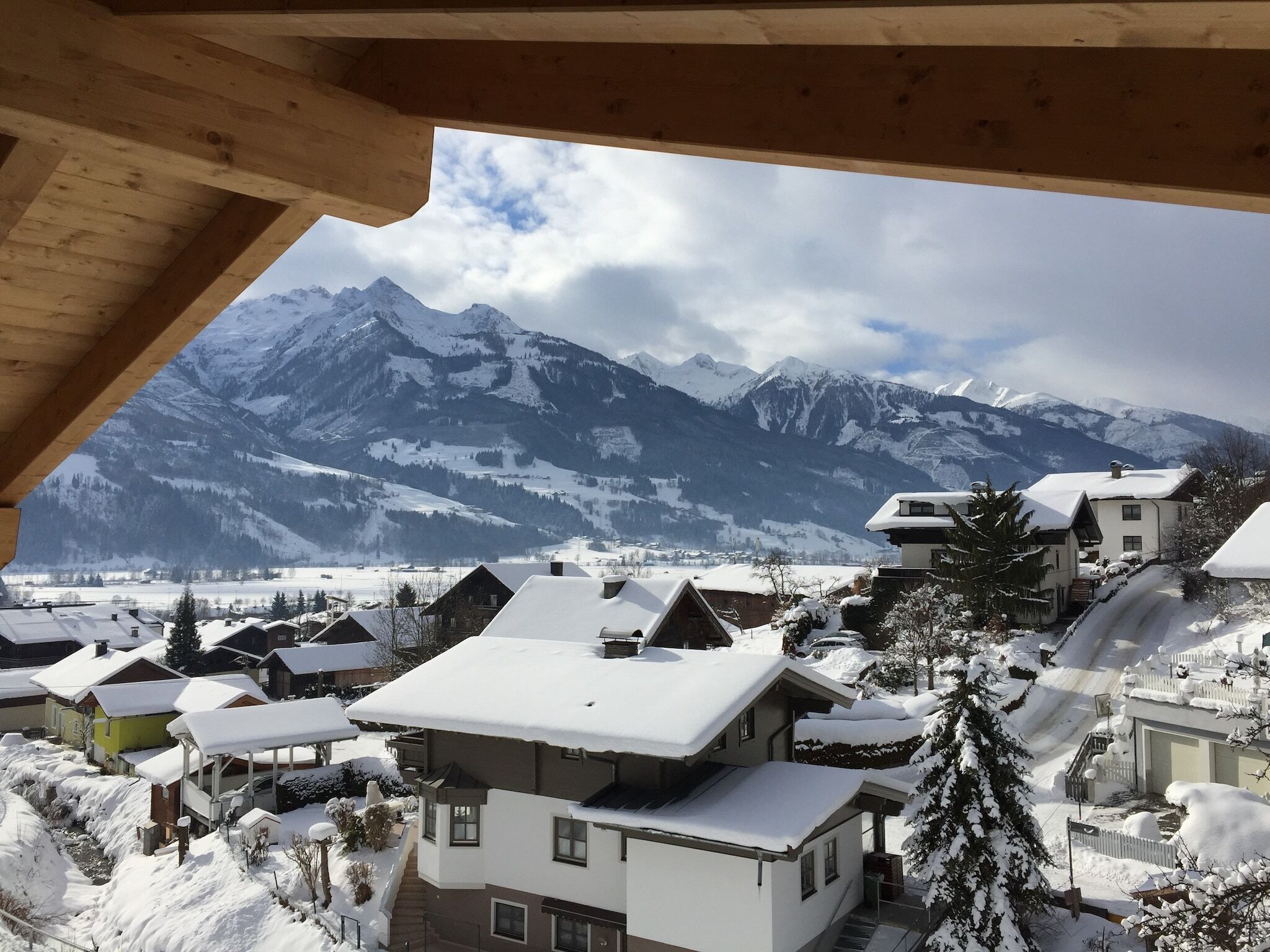A snow-covered mountain village with traditional wooden houses and a view of snow-capped peaks.