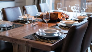 A dining table set with plates, glasses, and cutlery, with a view of a building through the window.
