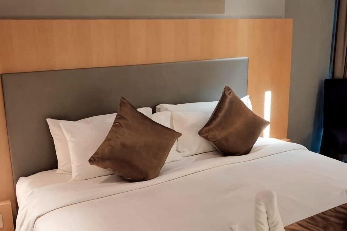 A bed with a wooden headboard, white bedding, and two brown pillows.
