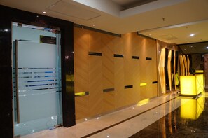 A modern hotel lobby with a glass elevator, wooden paneling, a reception desk, and a polished floor. - Greens Hotel & Suites (Bintulu)