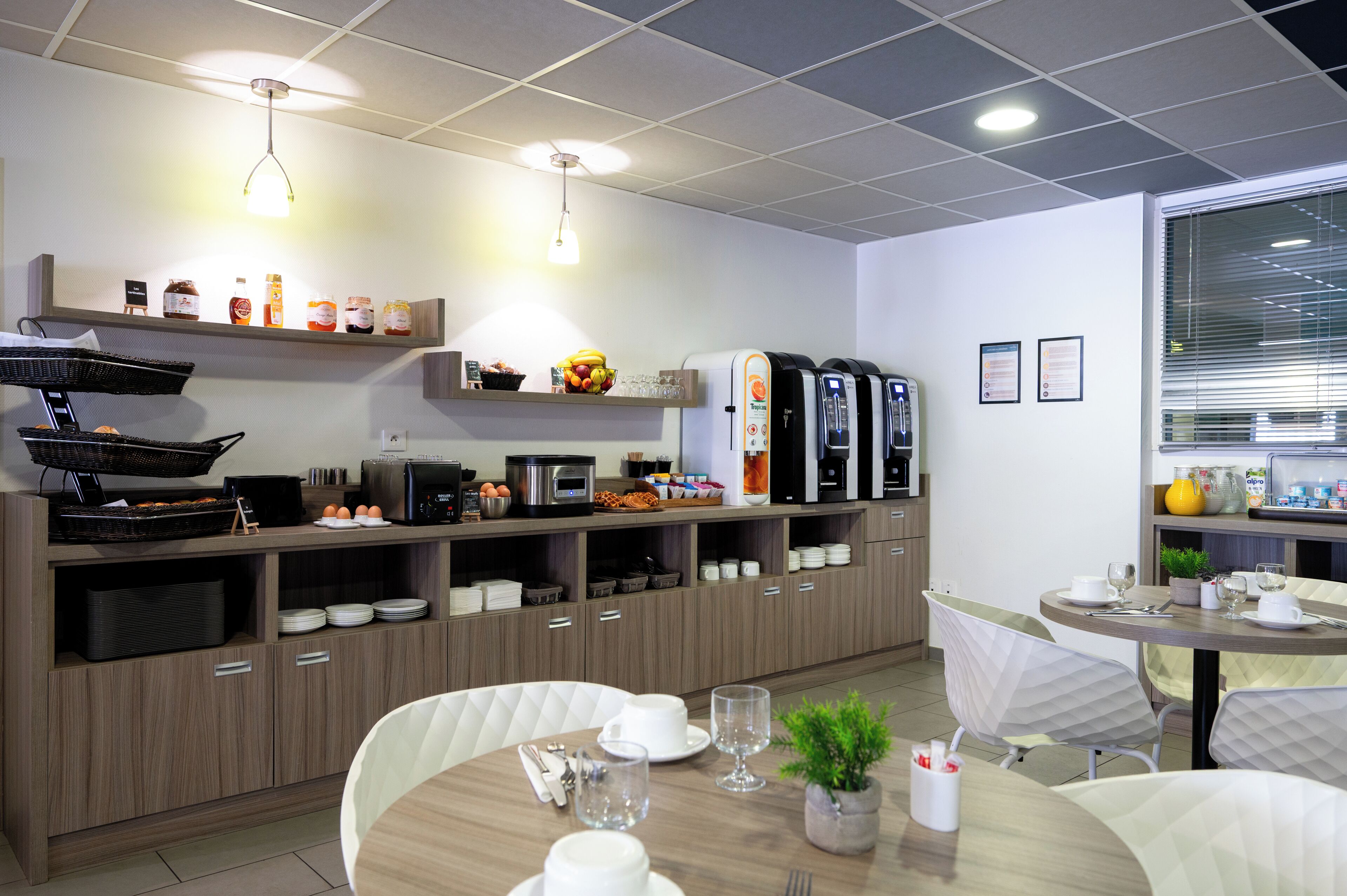 A modern kitchen with a buffet setup, including a microwave, coffee maker, and various food items.