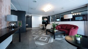 A modern lobby with a red sofa, a coffee table, and a lamp. - Nemea Appart Hotel Quai Victor Tours Centre (Tours)