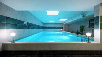 An indoor swimming pool with a tiled wall, a ceiling with recessed lighting, and a sign indicating the pool's depth.