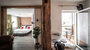 Ein Hotelzimmer mit Bett, einer kleinen Küchenzeile, einem Balkon mit Tisch und Stühlen und Blick ins Freie.