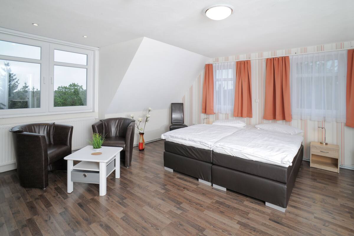 Une chambre à coucher avec un lit, une chaise, une petite table et une fenêtre.