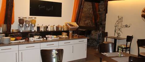 A dining area with a buffet setup, a chalkboard with writing, and a stone wall.