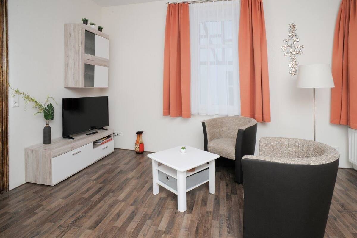 Un salon moderne avec un téléviseur, un meuble blanc et une petite table blanche.