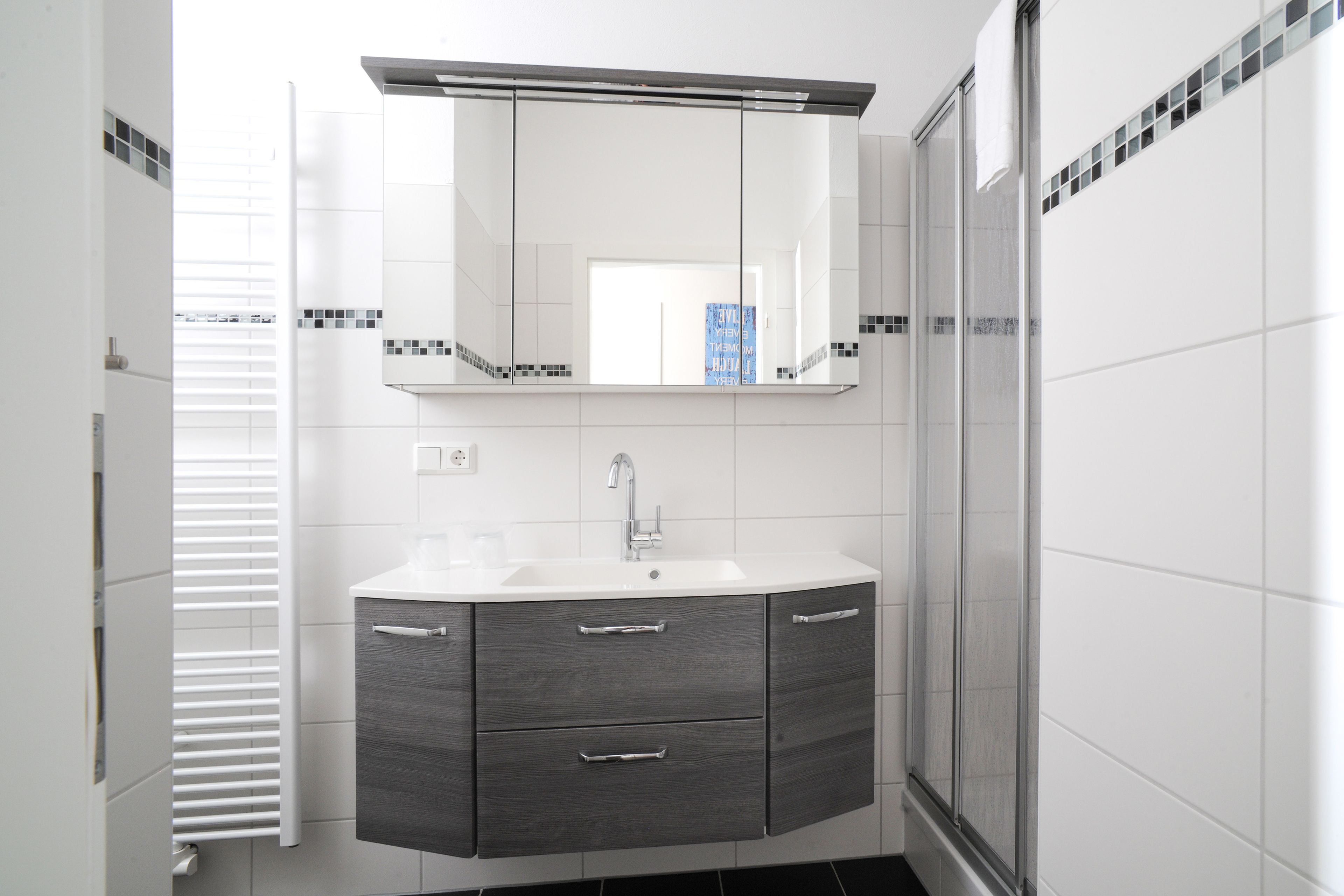A modern bathroom with a white sink, dark wooden vanity, and a large mirror above the sink.