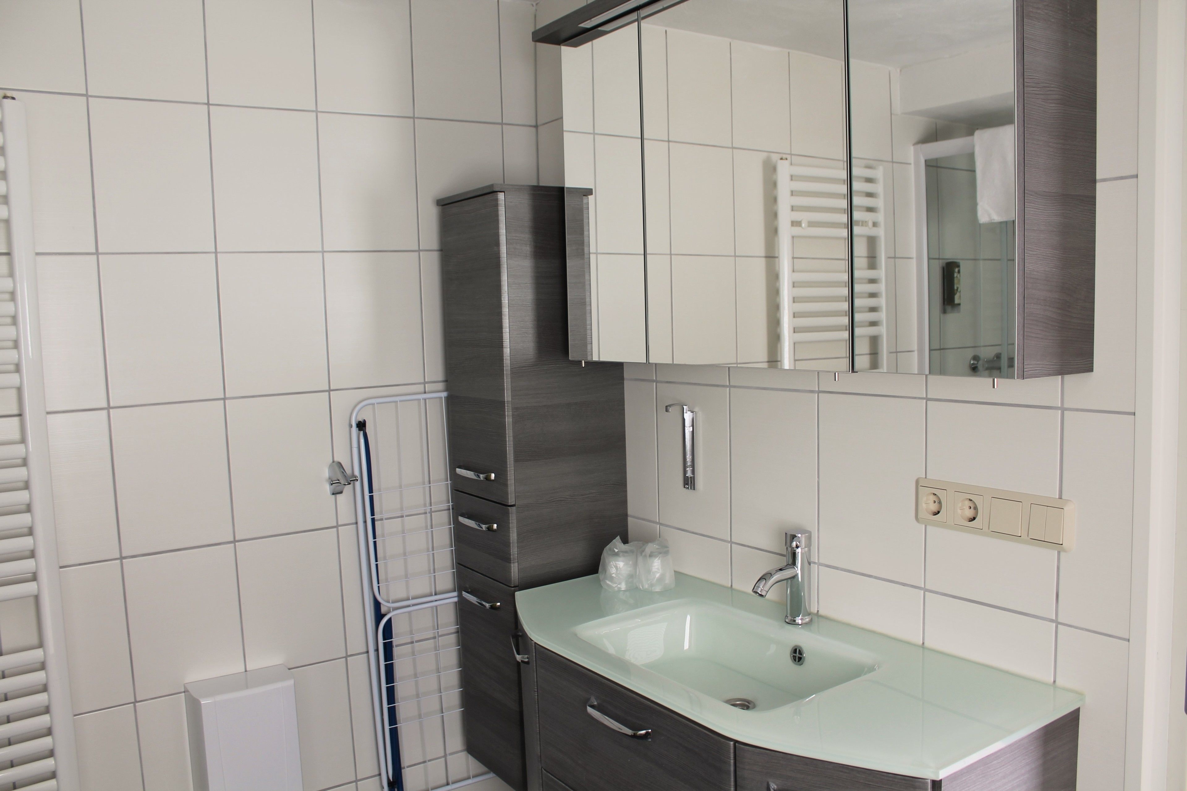 Un baño moderno con un lavabo de vidrio, armarios de madera oscura y un espejo grande.