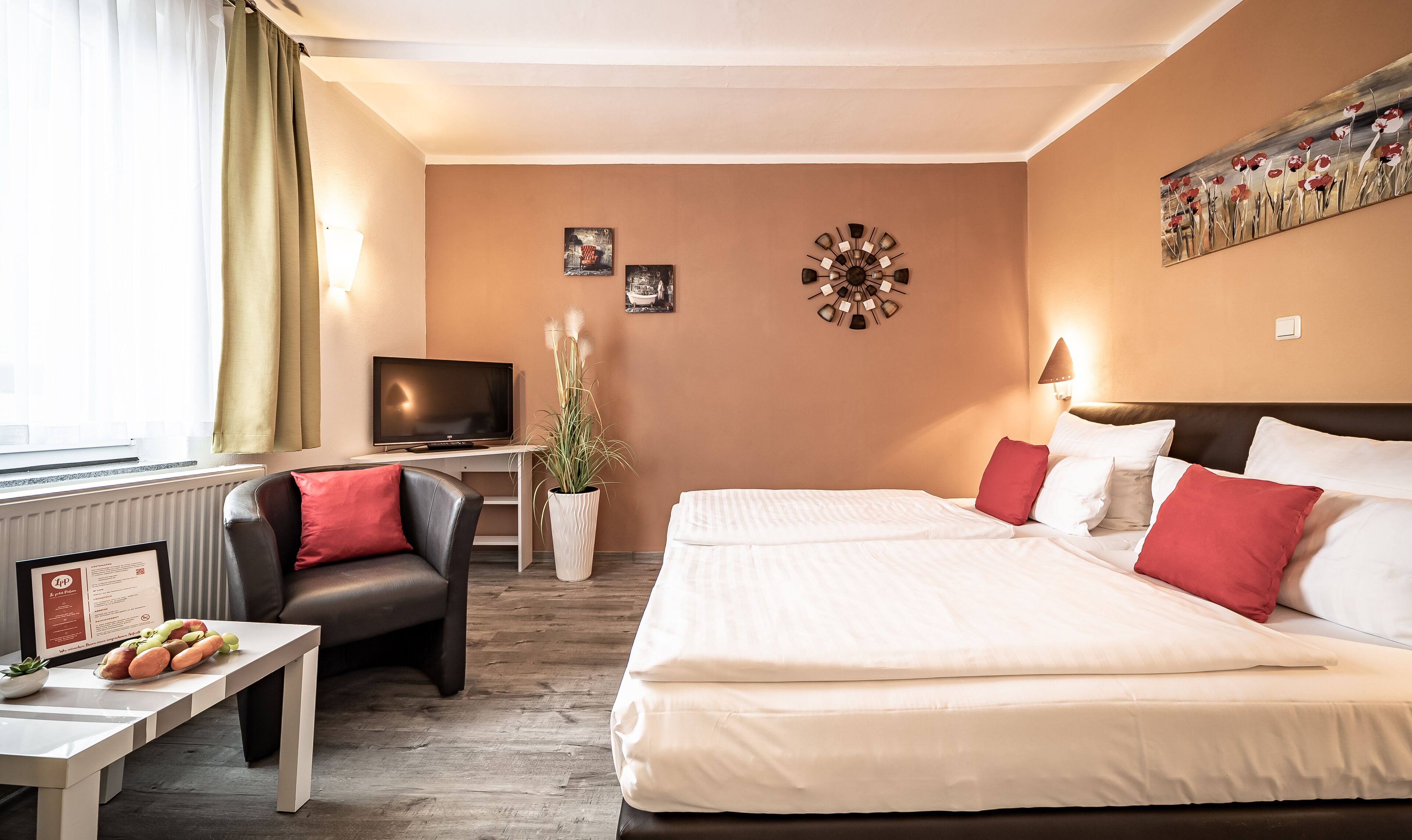 Une chambre d’hôtel comprenant un lit, une télévision, un bureau avec un menu, une chaise et une plante.
