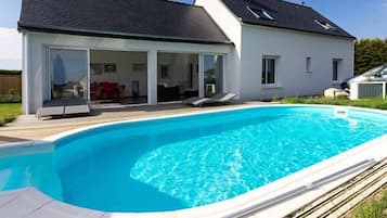 Een buitenzwembad, ligstoelen bij het zwembad