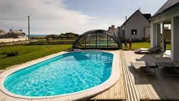 Een buitenzwembad, ligstoelen bij het zwembad