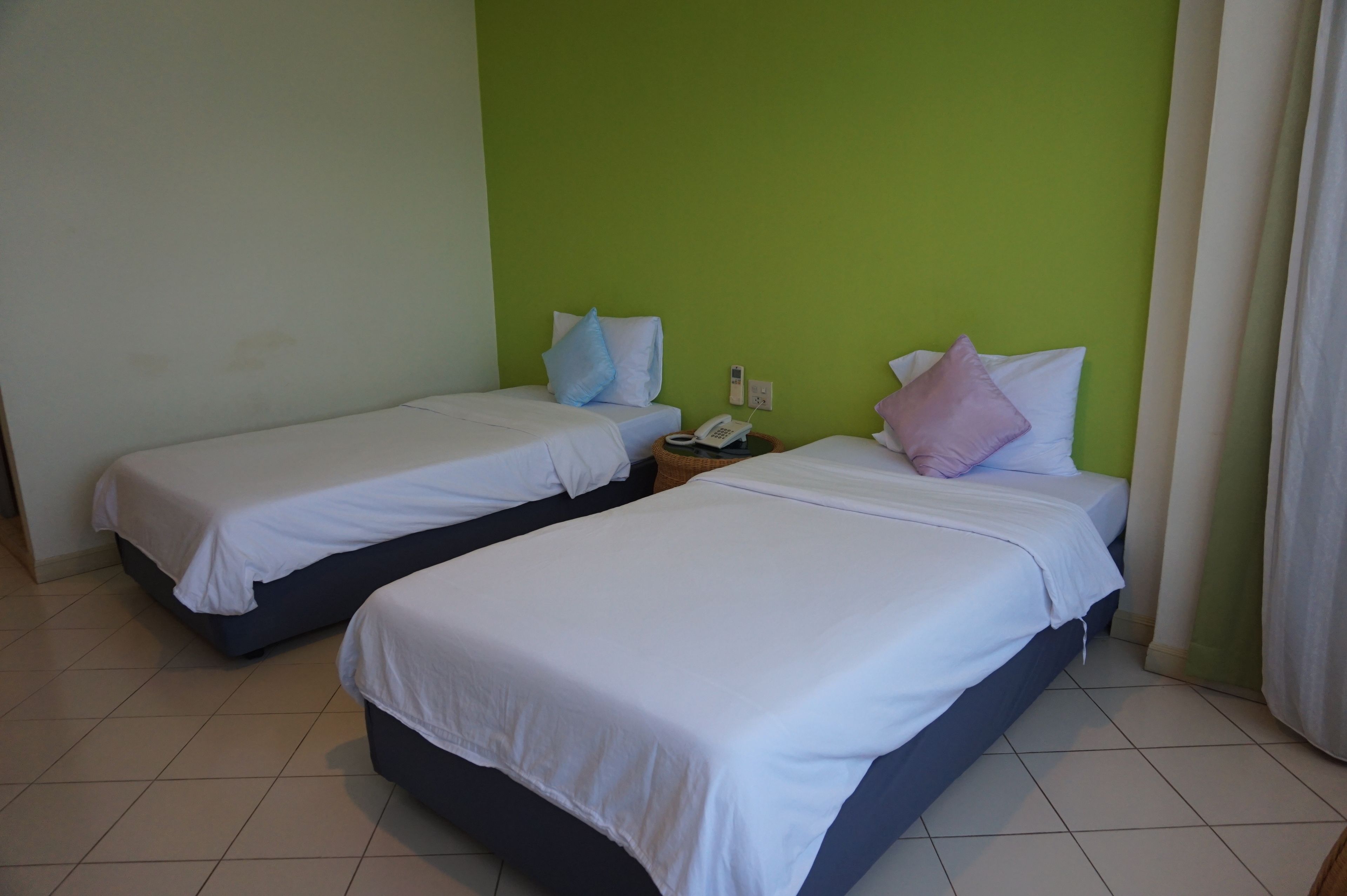 Two single beds with white linens, a bedside phone, and a nightstand.