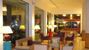 Un hall de hotel con varias zonas de estar, ventanas amplias y lámparas.