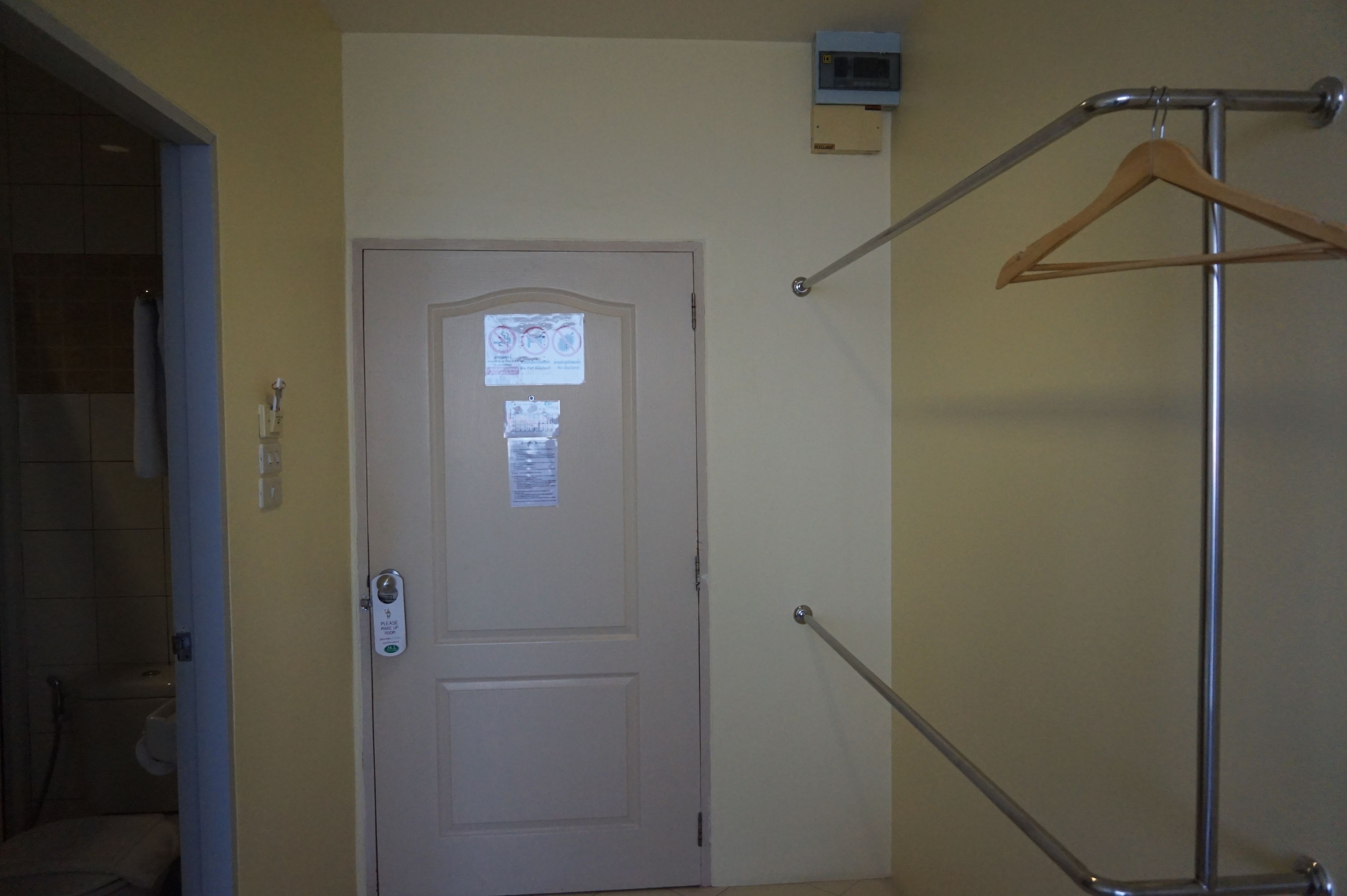 Una habitación de hotel con una puerta, un perchero y un equipo de aire acondicionado instalado en la pared.