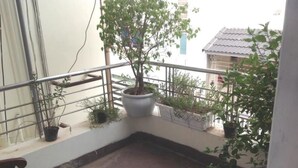 A balcony with a potted plant, a metal railing, and a tiled floor.
