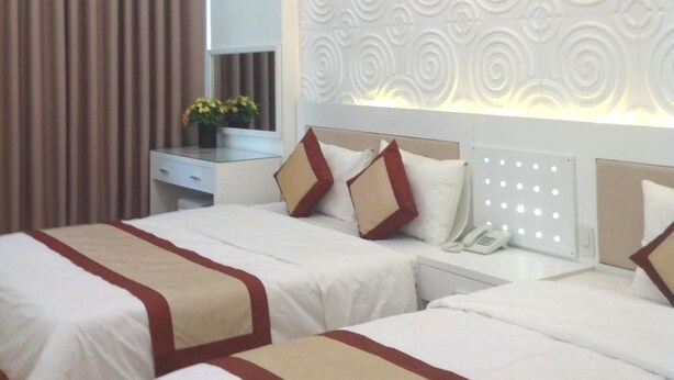 A hotel room with two beds, a bedside table with a phone, and a decorative wall panel.