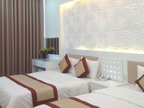 A hotel room with two beds, a bedside table with a phone, and a decorative wall panel.