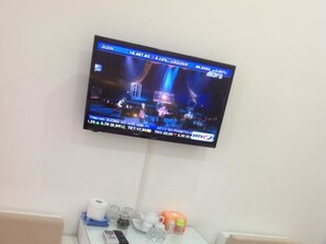 A television mounted on a wall displaying a news channel.