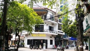 A street view with a coffee shop named 'TULU COFFEE' on the ground floor of a multi-story building. - New Hotel II (Hanoi)