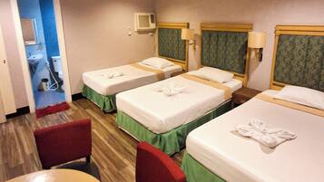 Una habitación de hotel con tres camas, una mesita y una silla.