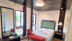Una habitación de hotel con cama, un banco, una mesita de noche, un espejo y una ventana.