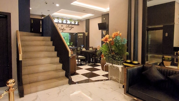 Un vestíbulo de hotel con piso a cuadros, una escalera, un sofá, un comedor y un letrero que dice 'Ridge Cafe'.
