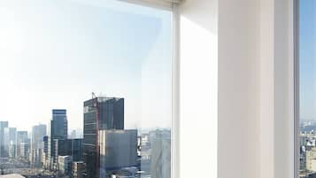 Una habitación moderna con un ventanal que ofrece vistas a la ciudad, un sofá cómodo y una pequeña mesa.