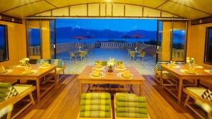 Un comedor con mesas y sillas, vista al mar y techo cubierto.