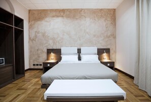 A modern hotel room with a large bed, two bedside tables with lamps, a wardrobe, and a wooden floor. - Guesthouse Vittoria Rooms (Genoa)