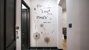 A hallway with a wall featuring inspirational phrases and dandelion illustrations. - Guesthouse Vittoria Rooms (Genoa)