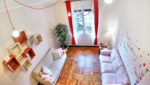 A cozy living room with a wooden parquet floor, two sofas, a bookshelf, and a wall with decorative elements. - Guesthouse Vittoria Rooms (Genoa)