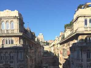 A street with historic buildings, a clear sky, and a distant building with a dome. - Guesthouse Vittoria Rooms (Genoa)