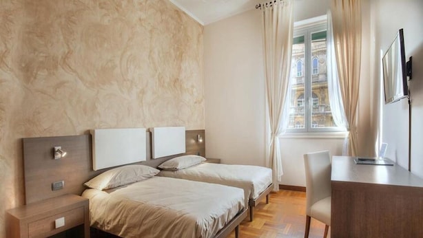 A hotel room with two beds, a desk, and a window with curtains. - Guesthouse Vittoria Rooms (Genoa)