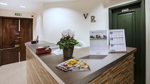 A reception desk with a plant, brochures, and a sign for Meridian Multiservice. - Guesthouse Vittoria Rooms (Genoa)