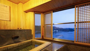 A traditional Japanese onsen with wooden walls and a view of a river and mountains. - Sun Urashima Yuki no Sato (Toba)