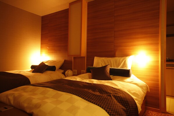 A hotel room with two beds, wooden paneling on the walls, and a nightstand with a lamp. - Sun Urashima Yuki no Sato (Toba)