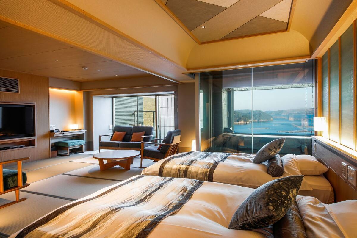 Habitación de hotel con una cama grande, televisión, zona de estar y vista al agua.