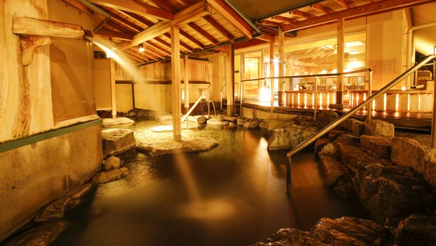 A traditional wooden interior with a hot spring area, stone steps, and a wooden staircase. - Sun Urashima Yuki no Sato (Toba)