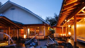 A traditional wooden building with a stone pathway leading to a hot spring area. - Sun Urashima Yuki no Sato (Toba)