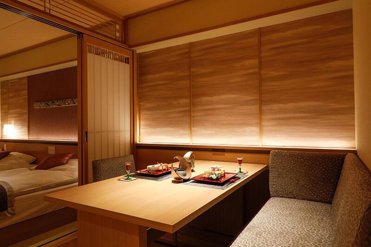 Una habitación japonesa tradicional con una mesa baja, asientos acolchados y un panel corredizo shoji.