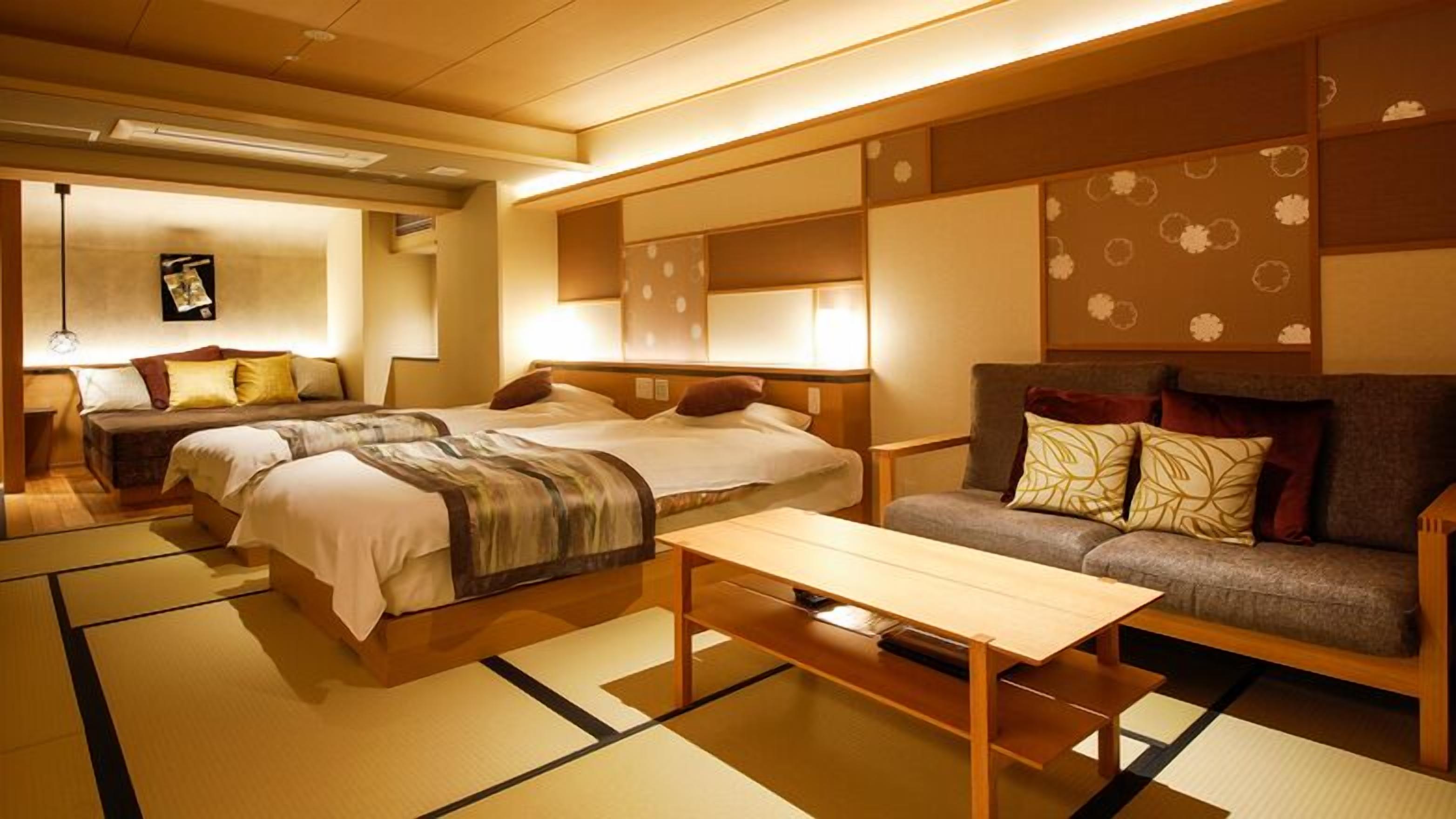Ein traditionell eingerichtetes Hotelzimmer im japanischen Stil mit Tatami-Böden, einer Couch, zwei Betten und einem kleinen Tisch.