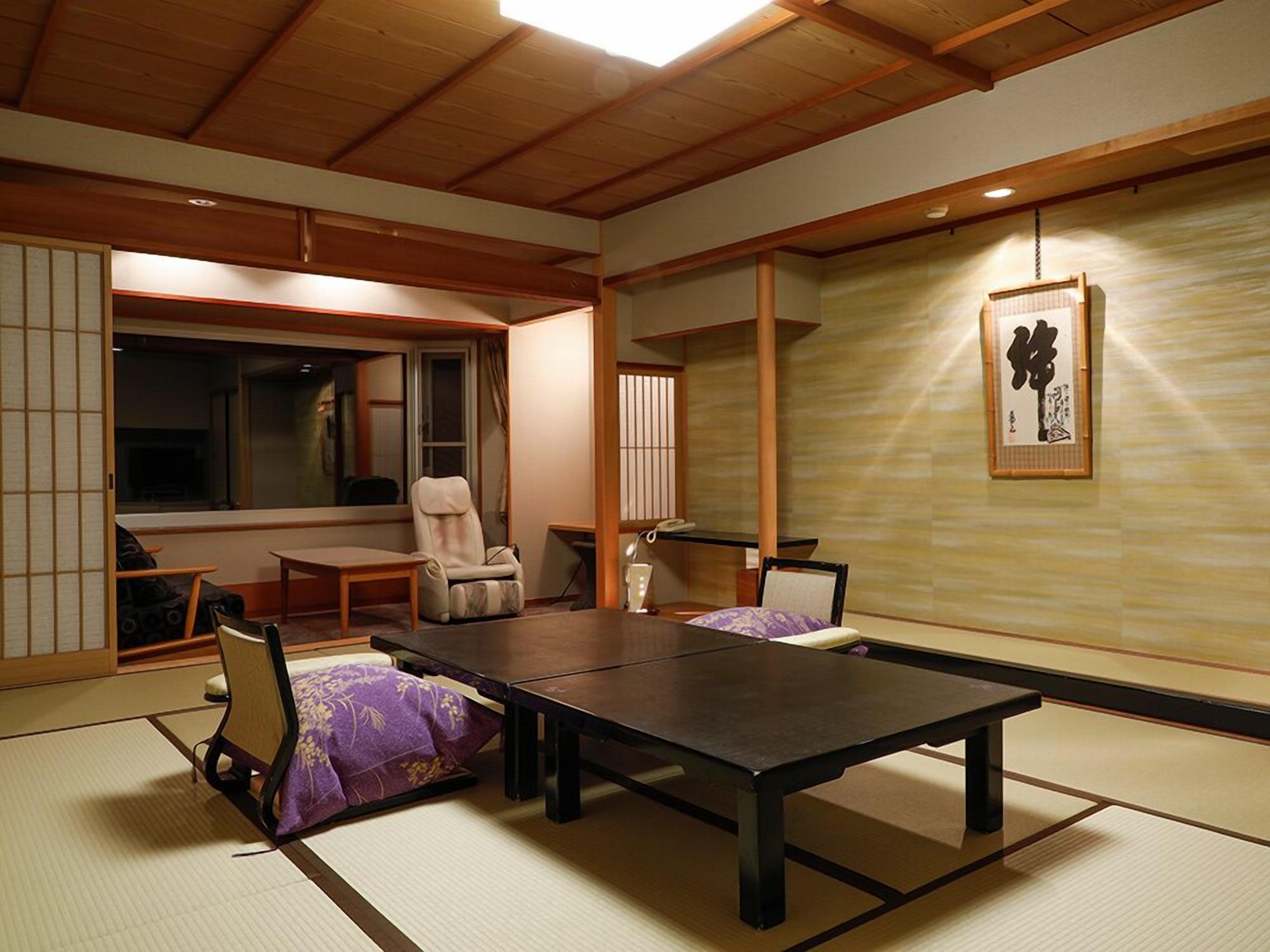 Um quarto japonês tradicional com tatames, uma mesa baixa, cadeiras e uma porta deslizante.