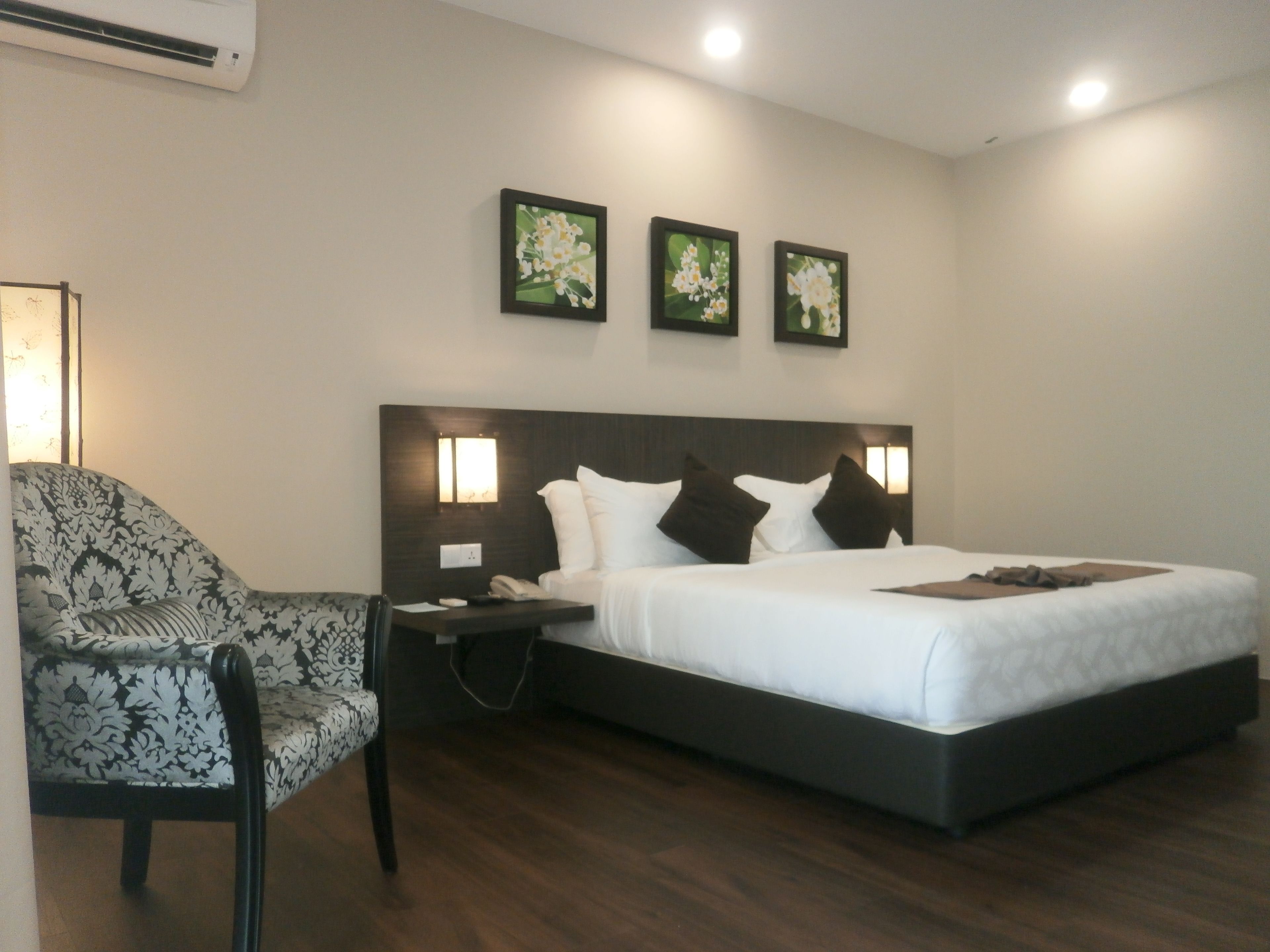A hotel room with a bed, a chair, and two wall-mounted lights.