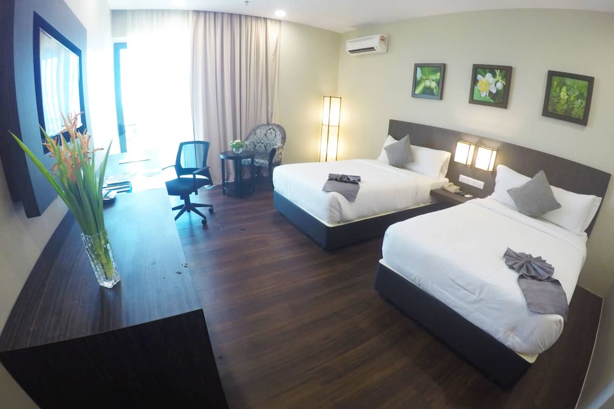 A hotel room with two beds, a desk, a chair, and a vase with flowers.