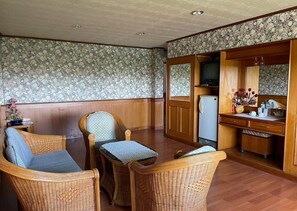 Ein Zimmer mit Korbmöbeln, einem Holzkabinett und einem Fernseher.
