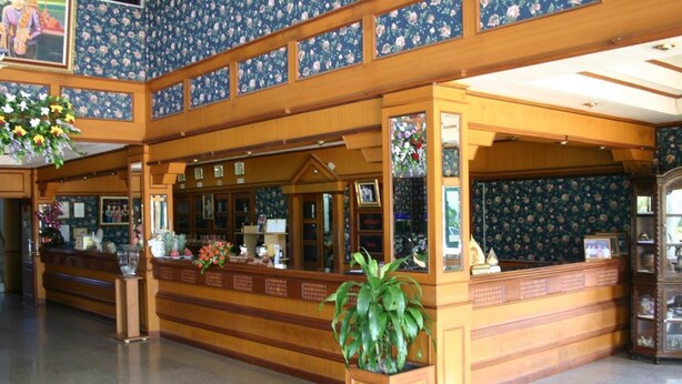 Un espace d’accueil avec un comptoir en bois, des décorations florales et une grande plante en pot.