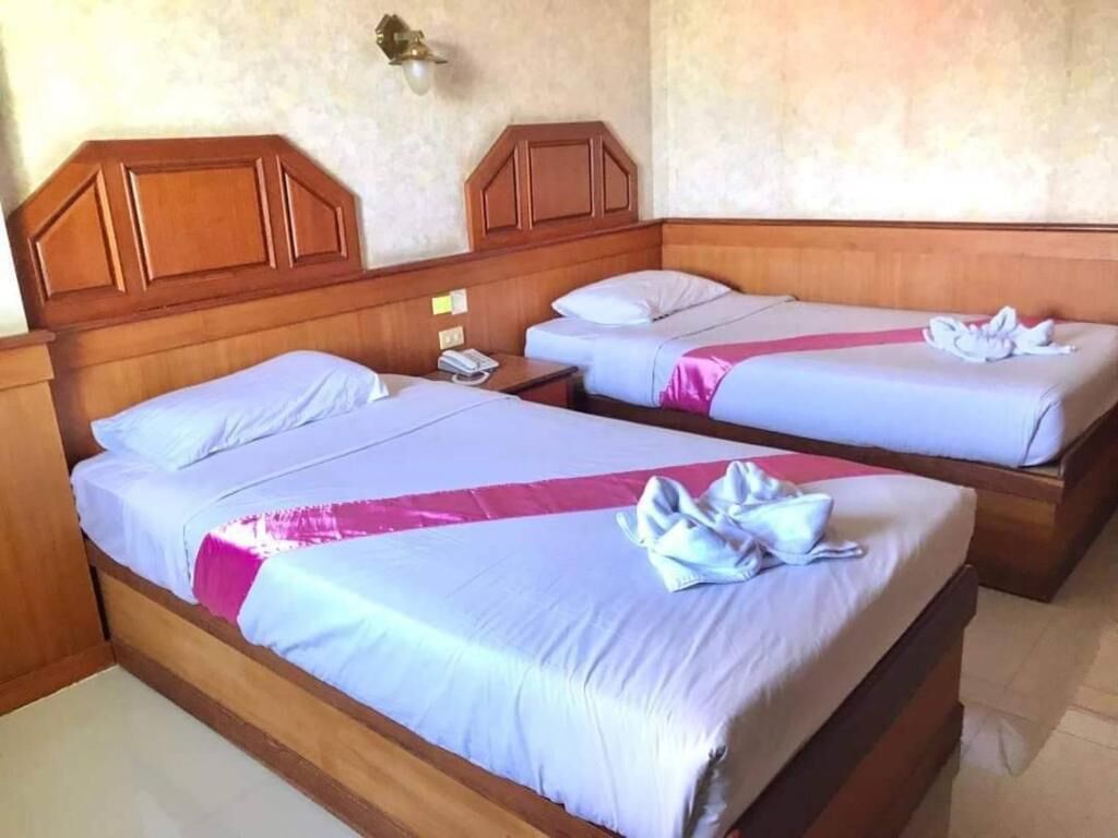 Quarto de hotel com duas camas, cabeceiras de madeira e mesa de cabeceira com telefone.